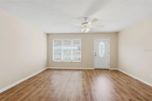 a view of an empty room with wooden floor and a window
