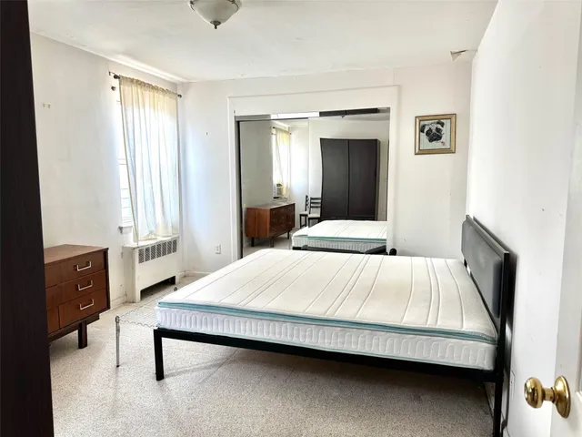 a bedroom with a bed a mirror and a window