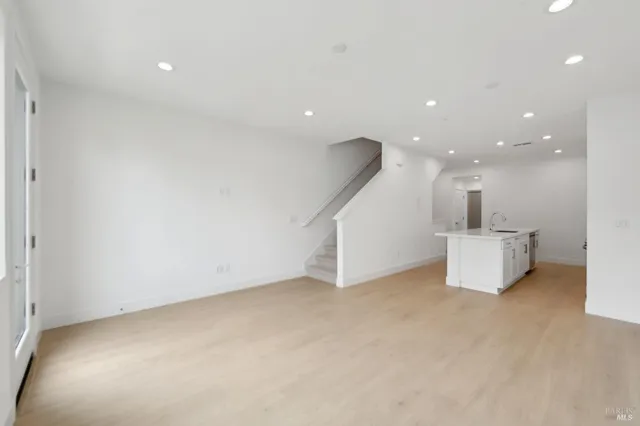 a view of an empty room with kitchen and a window
