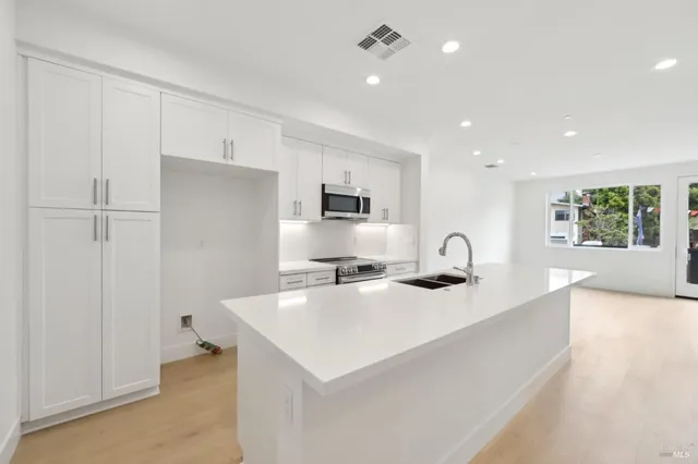 a kitchen with stainless steel appliances a refrigerator a sink a stove a microwave a counter top and cabinets