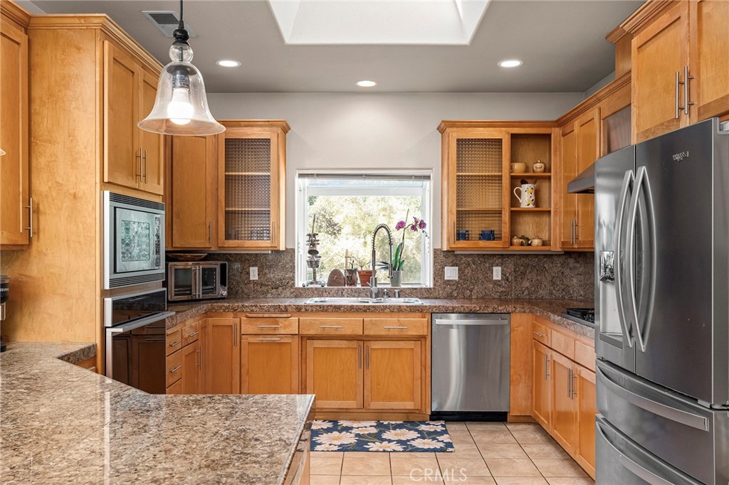 2262 Honey Run Road Chico, CA 95928 - Photo 74 of 74 Inside, the open floor plan offers spacious living with abundant natural light and expansive windows that frame the surrounding views. The living room features a cozy gas fireplace and ample space for gathering and entertaining. The kitchen is designed for both function and style, complete with granite countertops, stainless steel appliances, generous counter space, and bar seating, all enhanced by a skylight that fills the space with natural light.