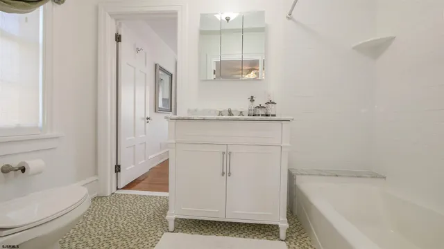 a bathroom with a granite countertop sink a toilet and bathtub
