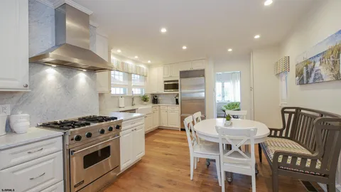 a kitchen with stainless steel appliances a white table chairs and a refrigerator