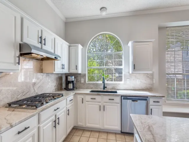 a kitchen with stainless steel appliances a sink a stove a counter space and a window