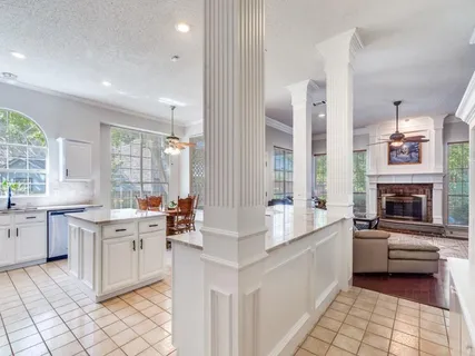 a large white kitchen with a stove a sink dishwasher and a fireplace
