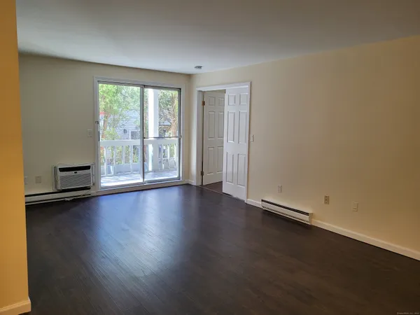 an empty room with wooden floor chandelier and windows