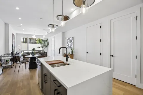 a large kitchen with kitchen island a stove a sink a dining table and chairs with wooden floor