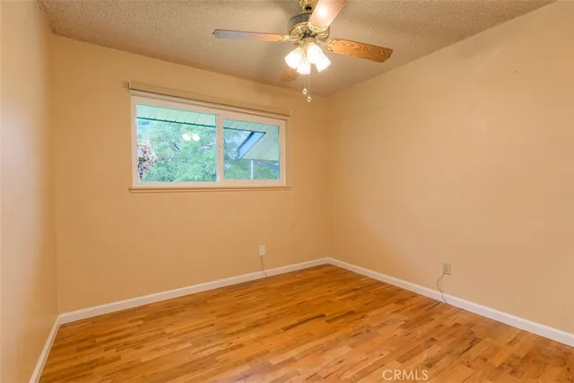 a view of empty room with wooden floor and fan