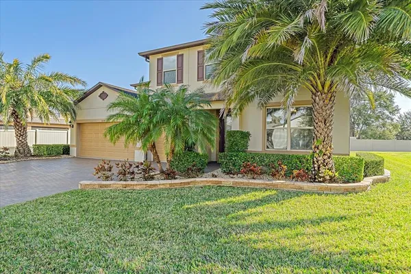a view of a house with a yard and palm trees