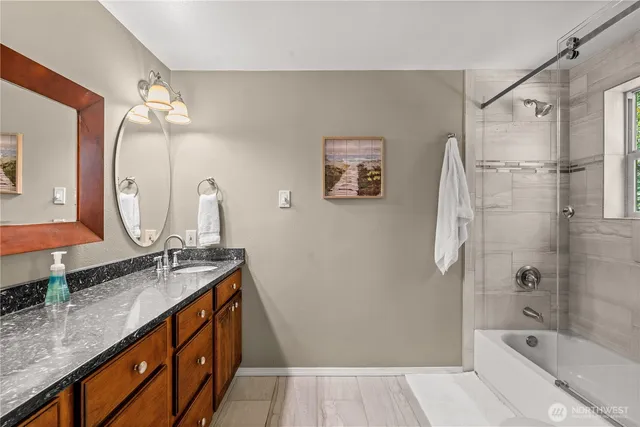 a bathroom with a granite countertop sink a toilet a mirror a vanity and shower