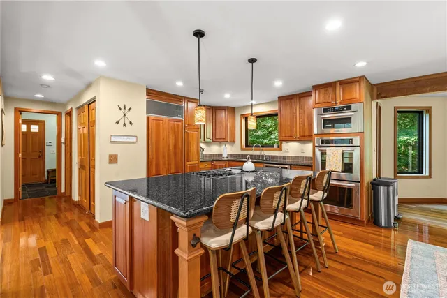 a kitchen with stainless steel appliances granite countertop a kitchen island a stove a refrigerator a sink with a dining table and chairs