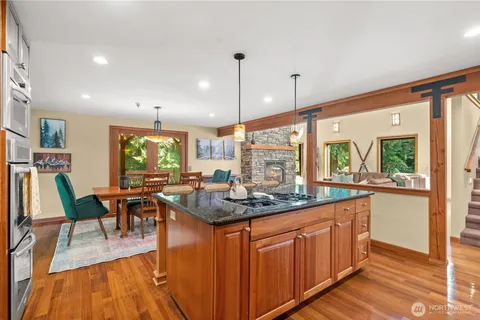 a kitchen with stainless steel appliances granite countertop sink stove dining table chairs and wooden floor