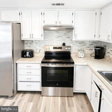 a kitchen with stainless steel appliances granite countertop a sink stove and white cabinets