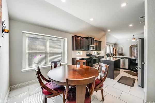 a dining room with stainless steel appliances kitchen island granite countertop a dining table and chairs