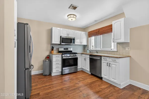 a kitchen with stainless steel appliances granite countertop a stove a sink dishwasher and a refrigerator with wooden floor