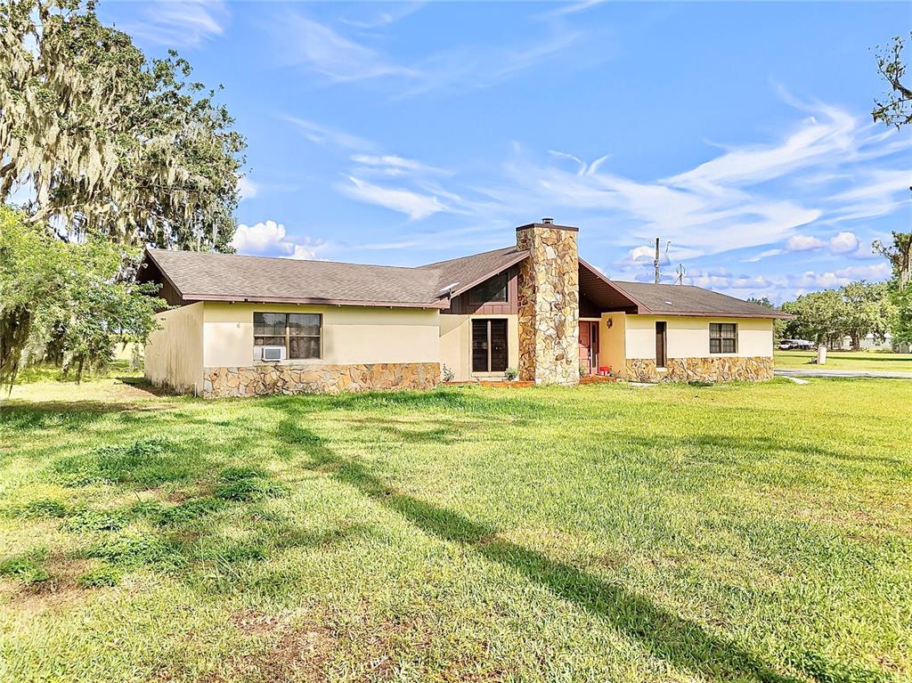 a view of a yard in front of a house with a large tree