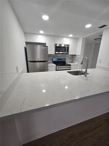 a large kitchen with kitchen island a sink dishwasher a refrigerator and a stove