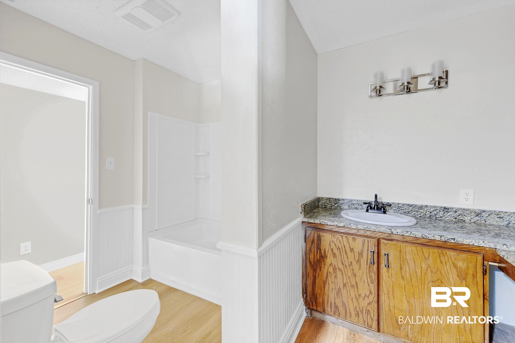 11964 Stroh Road Daphne, AL 36527 - Photo 34 of 58 Bathroom with vanity, visible vents, a wainscoted wall, toilet, and wood finished floors