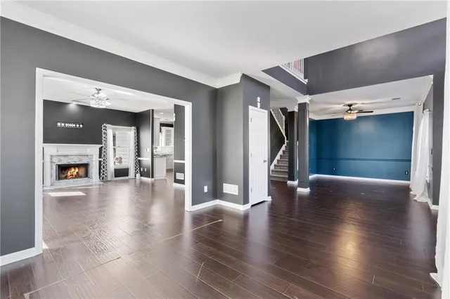 a view of an empty room with wooden floor fireplace and a window