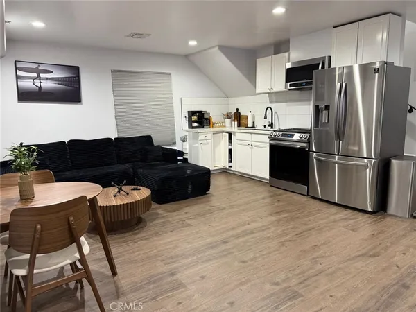 a kitchen with stainless steel appliances granite countertop a refrigerator a stove a sink dishwasher and a microwave with wooden floor