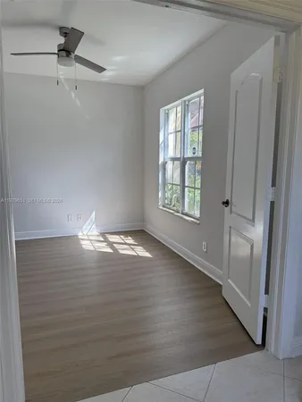 a view of empty room with wooden floor and fan