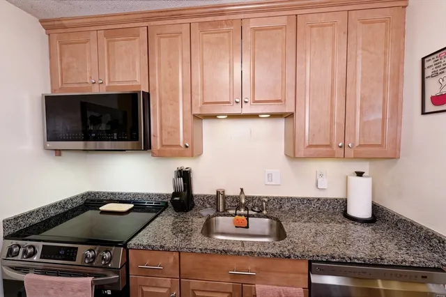 a kitchen with granite countertop a sink dishwasher stove and cabinets