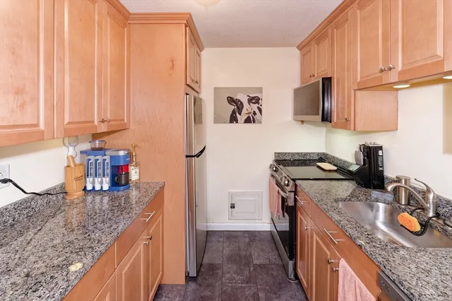 a kitchen with granite countertop a sink stove and refrigerator