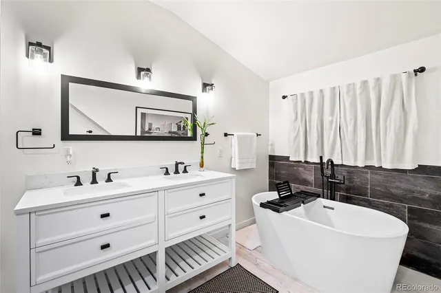 a bathroom with a double vanity sink a mirror and a bathtub