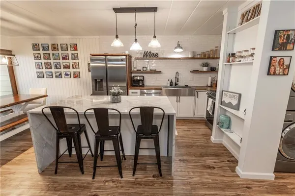 a kitchen with stainless steel appliances granite countertop a table chairs and a refrigerator