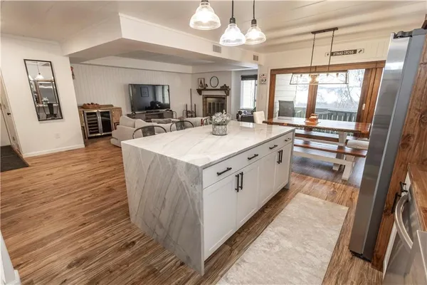 a large white kitchen with wooden floor and a fireplace