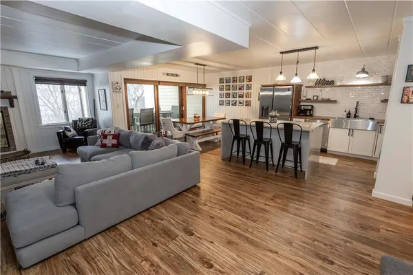 a living room with furniture a wooden floor and kitchen view