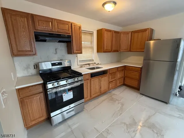 a kitchen with stainless steel appliances granite countertop a stove a sink and a refrigerator