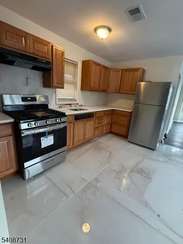 a kitchen with stainless steel appliances granite countertop a stove a sink and a refrigerator