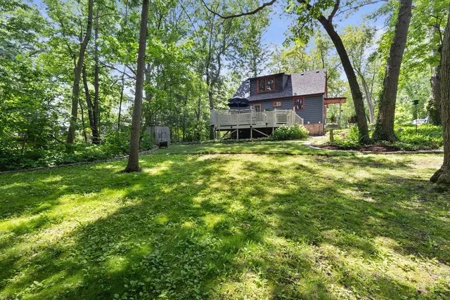 a brick house with a big yard plants and large trees