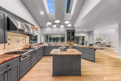 a large kitchen with stainless steel appliances a stove a sink dishwasher and cabinets with wooden floor