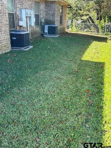 a backyard of a house with large trees and wooden fence