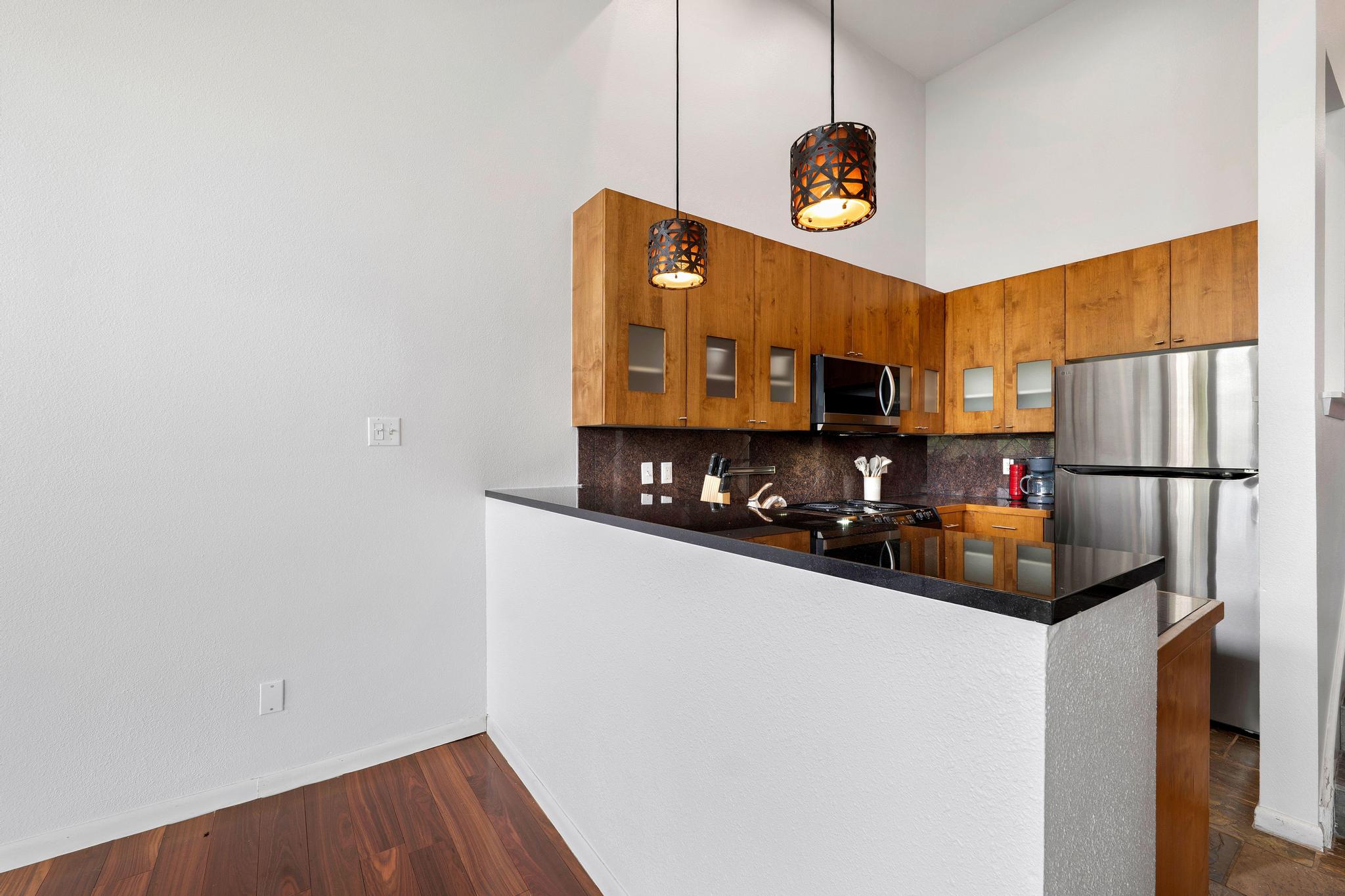 2918 Ranch Road 620, Unit J162 Austin, TX 78734 - Photo 9 of 26 Kitchen featuring wood cabinetry with frosted glass accents, dark stone countertops, stainless steel appliances, and wood-finish flooring