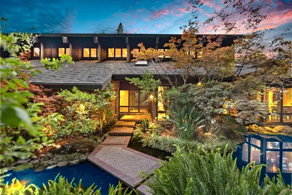 a backyard of a house with large trees and plants