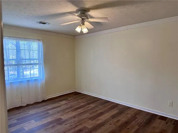 an empty room with wooden floor chandelier fan and windows