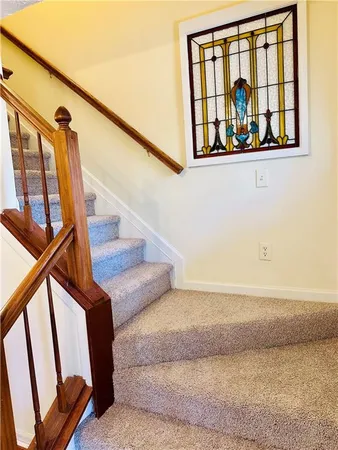 a view of staircase with lots of frames on wall and a window