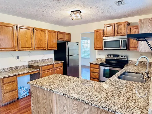 a kitchen with stainless steel appliances granite countertop a refrigerator stove top oven and sink
