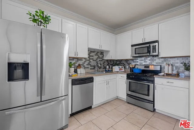 a kitchen with white cabinets stainless steel appliances and a potted plant