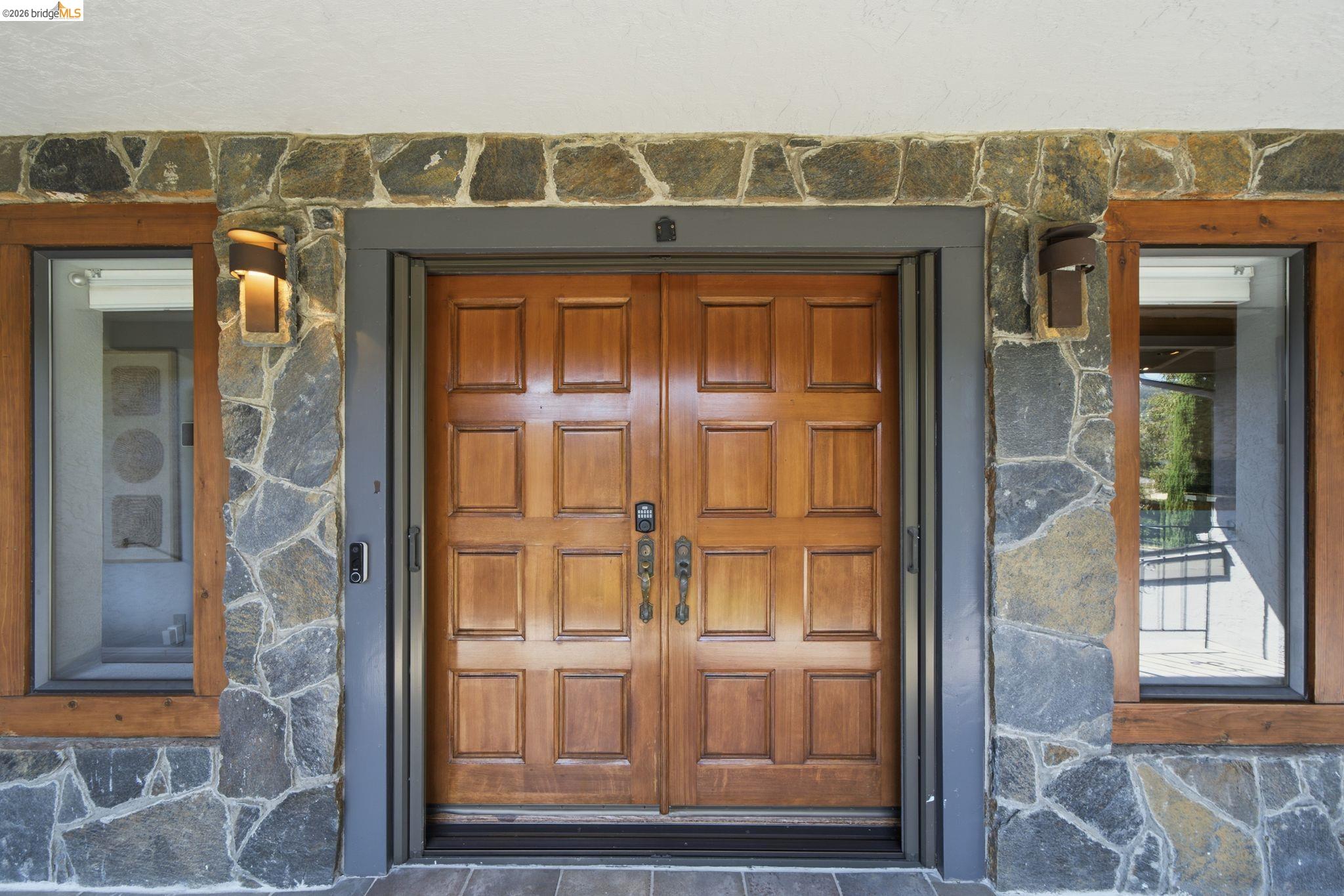 11133 Golf Links Road Oakland, CA 94605 - Photo 7 of 57 Double wooden panel doors framed by stone veneer siding and wood-framed windows