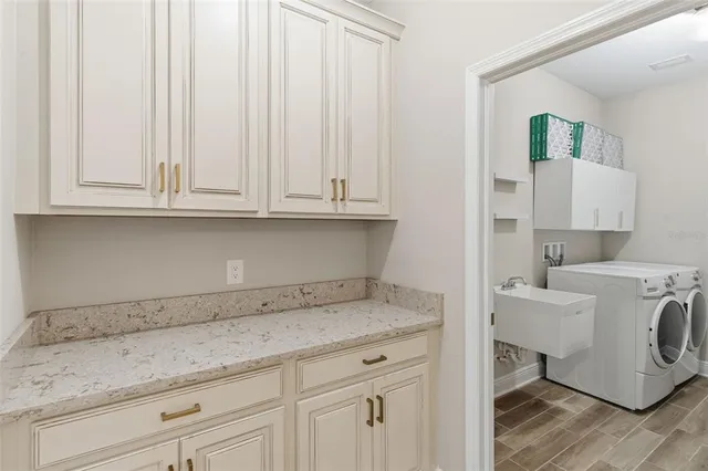 a utility room with granite countertop white cabinets and a sink