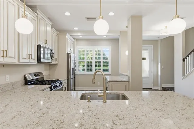 a kitchen with stainless steel appliances granite countertop a sink a stove and a granite counter tops with white cabinets