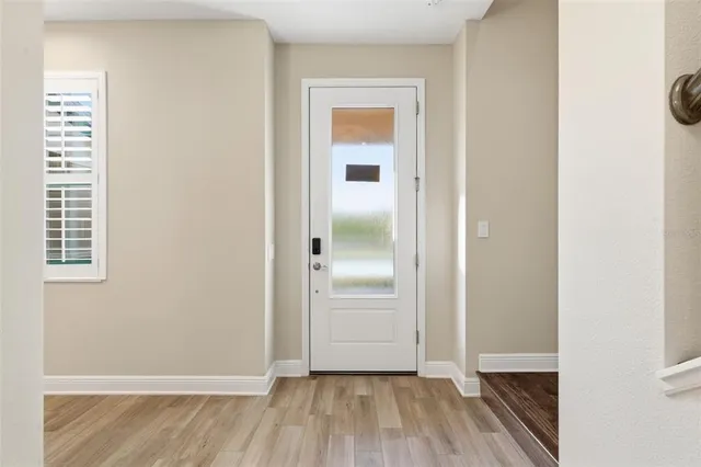 an empty room with wooden floor closet and windows