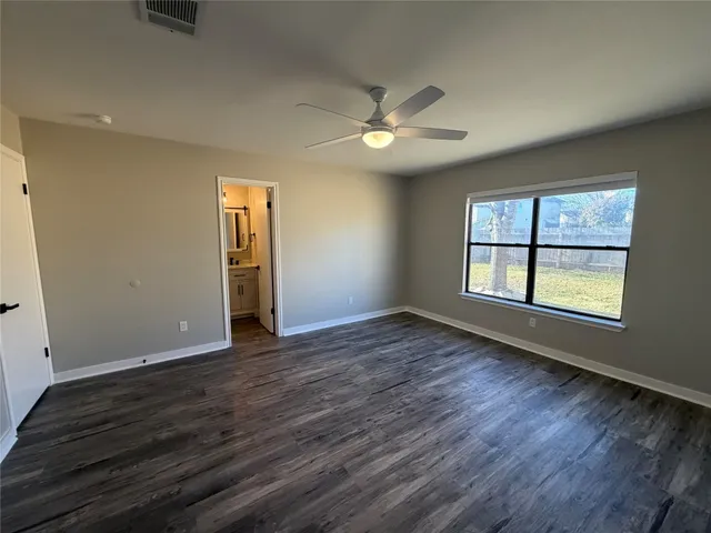 an empty room with wooden floor chandelier fan and windows