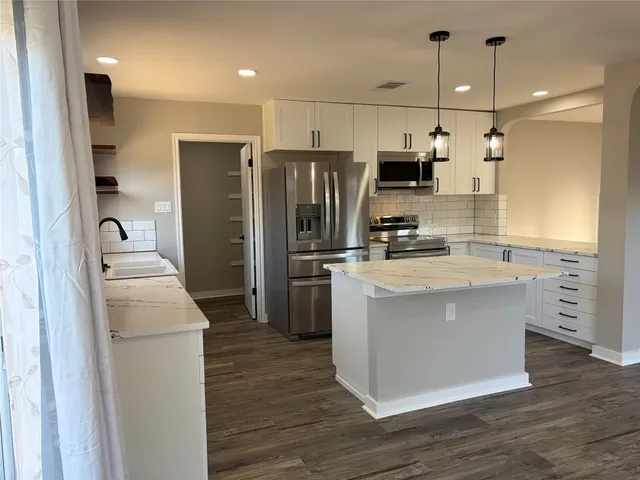 a kitchen with a refrigerator sink and wooden cabinets