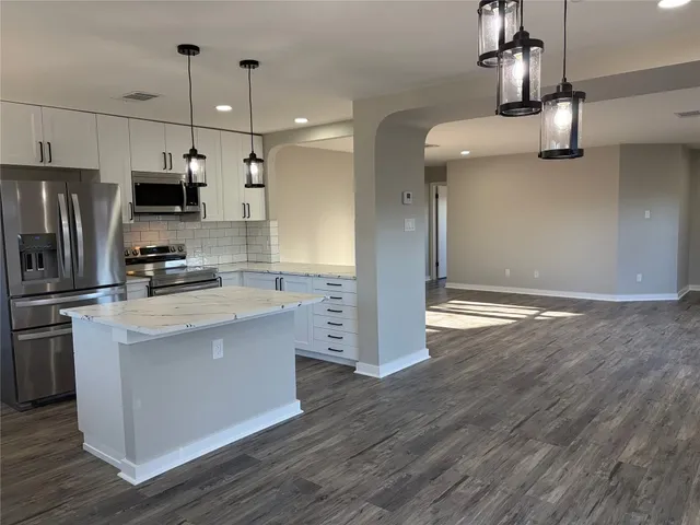 a kitchen with stainless steel appliances granite countertop a refrigerator a stove a sink and a microwave