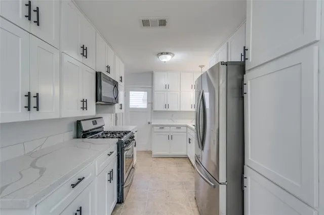 a kitchen with stainless steel appliances granite countertop a refrigerator a stove and a sink